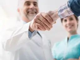 Stretta di mano tra un medico e una collega in camice