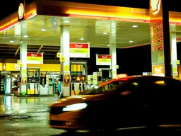 Distributore di carburante di notte, con un'auto in transito