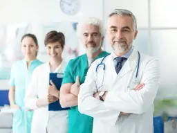 Quattro professionisti sanitari in camice, con il medico in primo piano